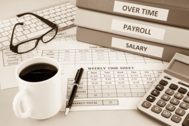 Human resources documents: payroll, salary and employee time sheets place on office table with cup of coffee and calculator, sepia tone